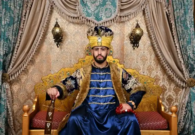 Man wearing a traditional Ottoman sultan costume seated on an ornate throne in Istanbul