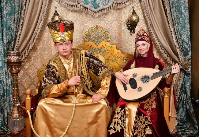 Couple wearing traditional Ottoman costumes with an oud in an ornate palace-style setting in Istanbul